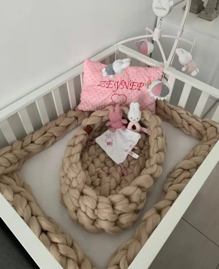 Merino wollen bedbumper van BELM in warmwitte kleur, decoratief gestileerd met babykamer accessoires